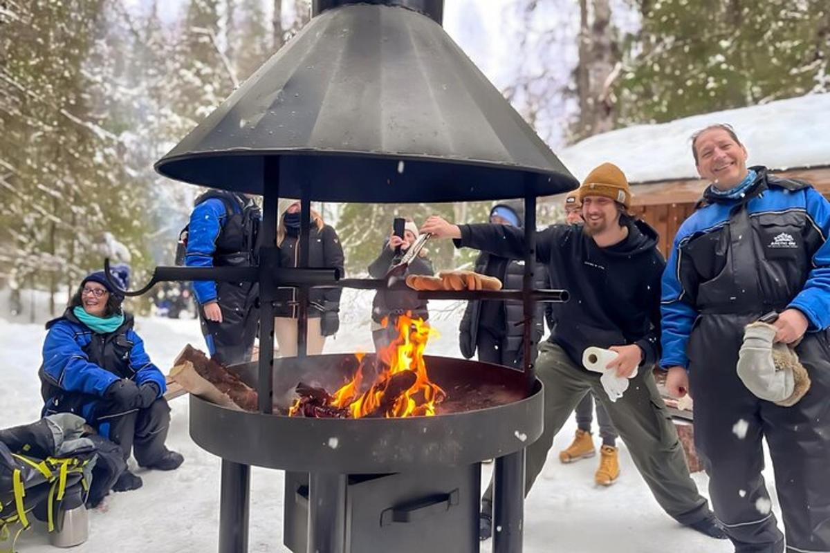 a group of people standing around a grill in the snow