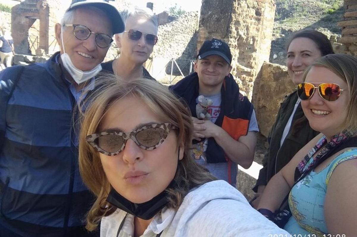 Un grupo de personas de pie alrededor de una mujer que lleva gafas de sol.