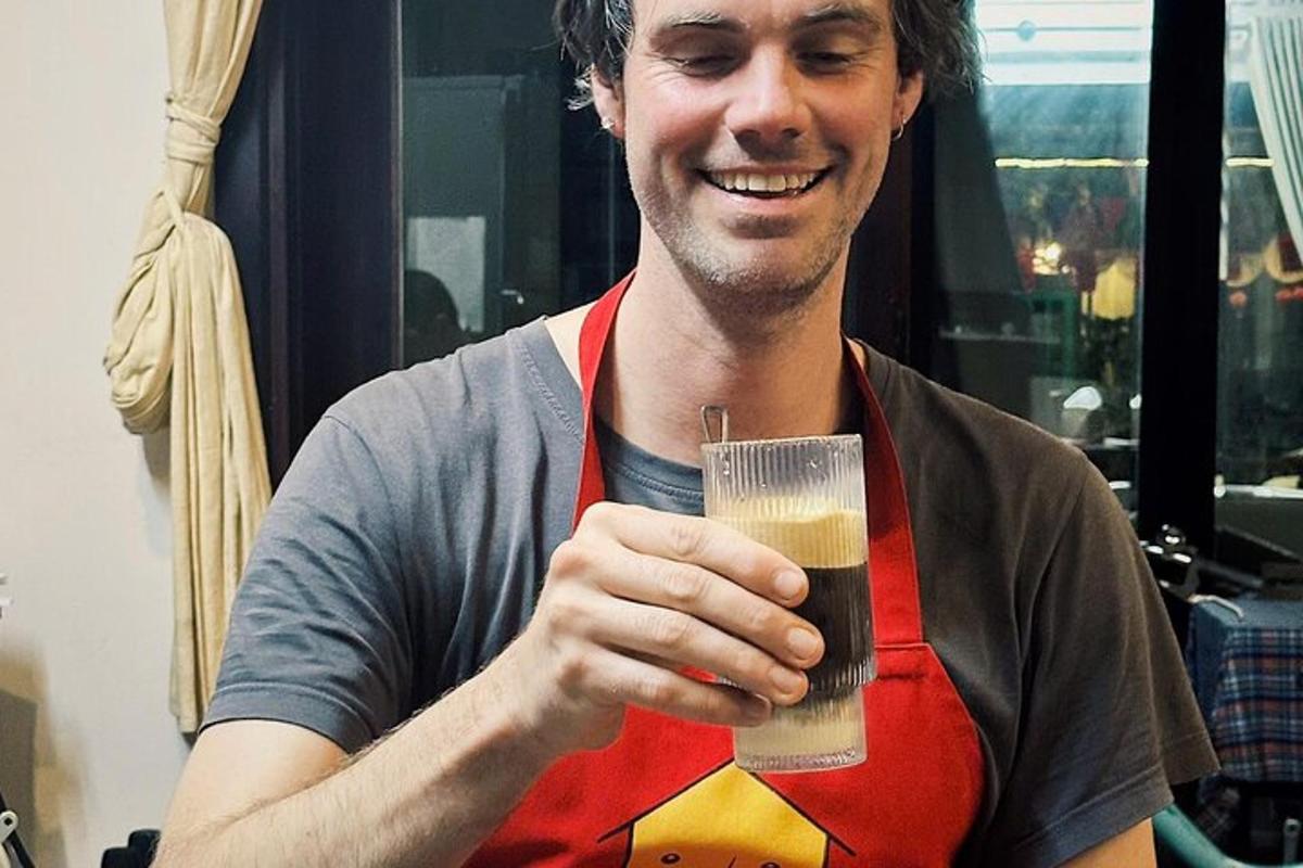 un home amb davantal que sosté un got de cervesa
