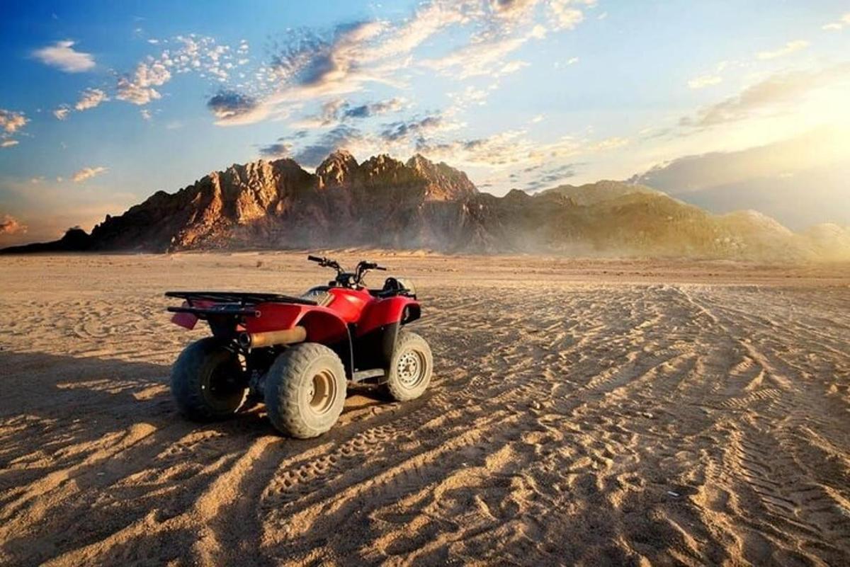 Un vehículo todo terreno rojo estacionado en la arena del desierto.