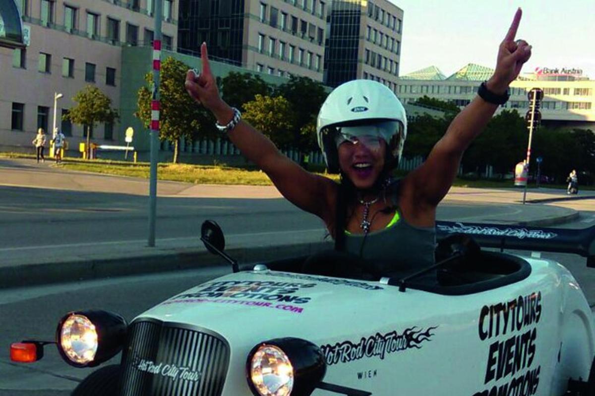 žena jedoucí na motorce s rukama ve vzduchu