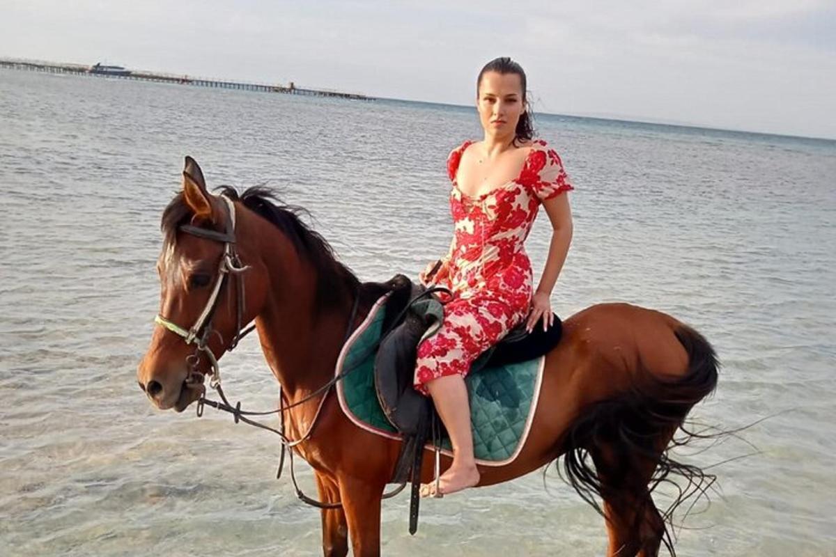 una donna in abito a cavallo sulla spiaggia