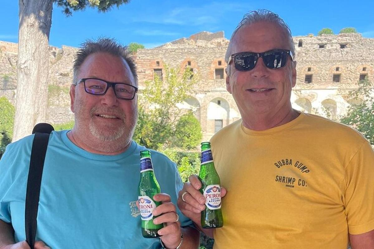 due uomini in piedi uno accanto all'altro con in mano bottiglie di birra