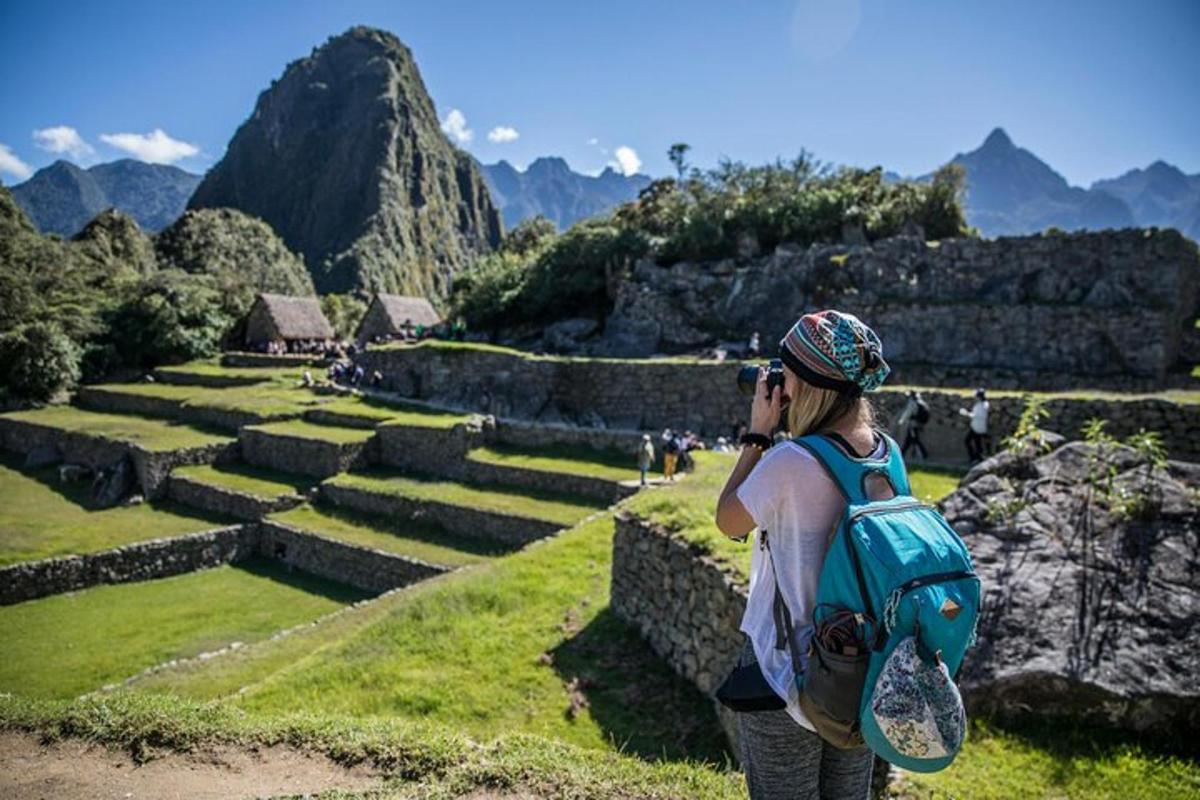 a woman with a backpack taking a picture of an ancient ruins