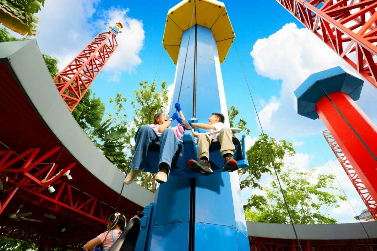 două persoane care călătoresc pe un roller coaster într-un parc tematic