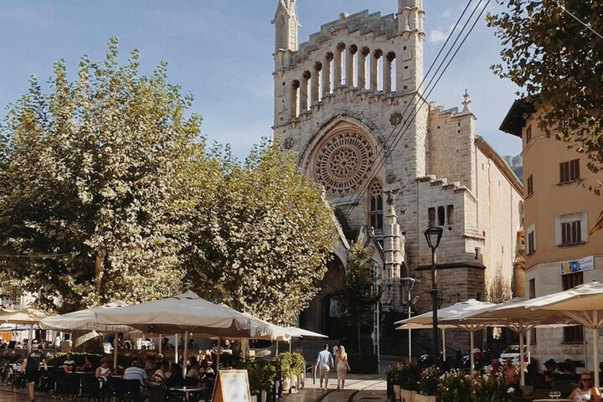 ēka ar katedrāli, galdiem un saulessargiem