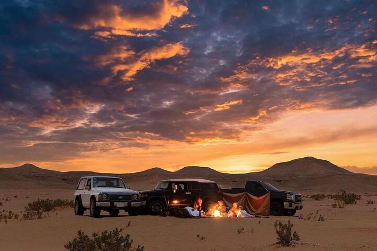 Un grupo de personas sentadas alrededor de una fogata en el desierto.