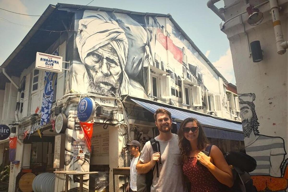 duas pessoas em pé em frente a um prédio com um mural