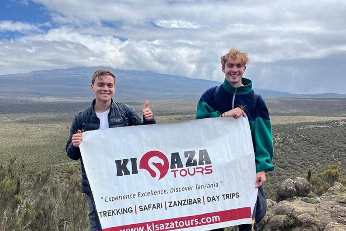 dois homens segurando uma placa no topo de uma montanha