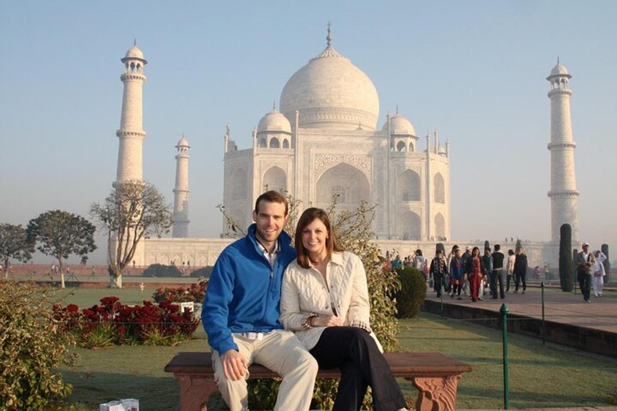 a man and a woman sitting on a bench in front of the taj mah