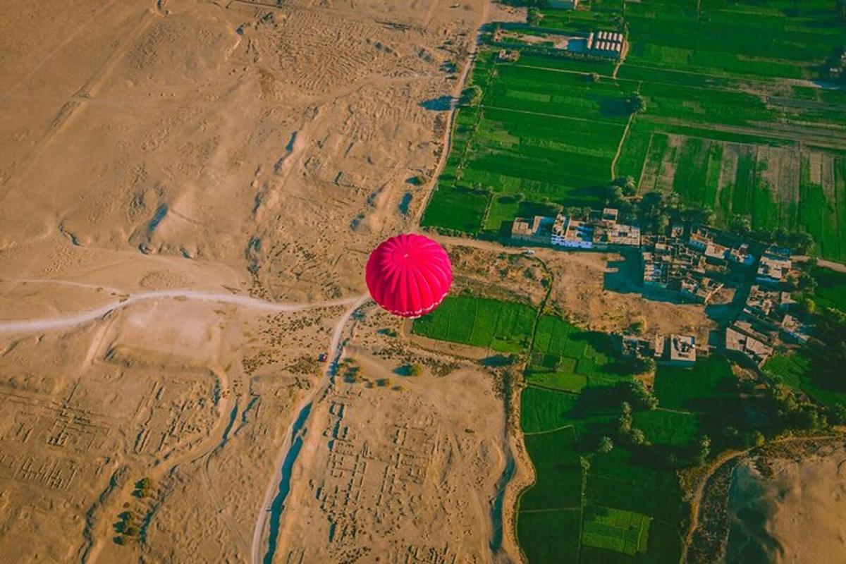 a red balloon flying in the air over a field