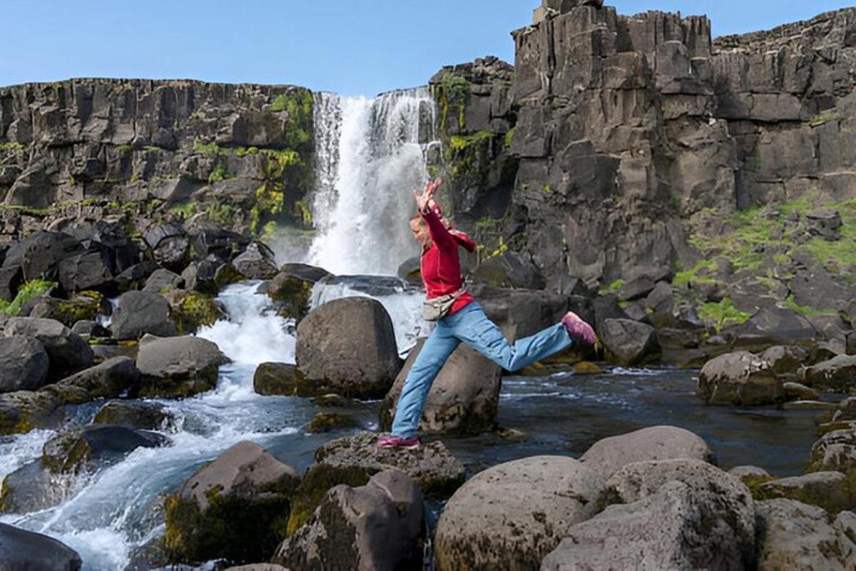 a woman standing on a rock in front of a waterfall