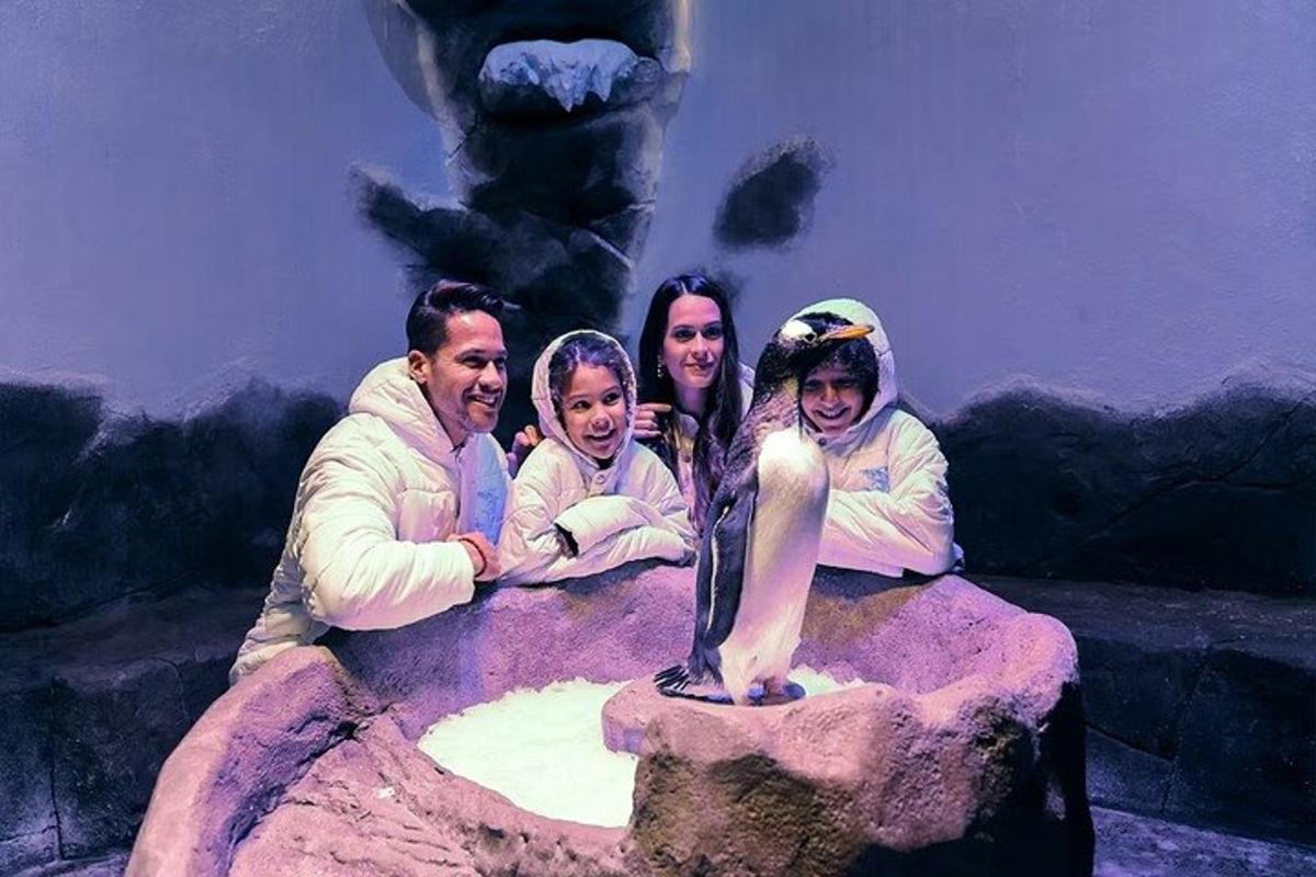 a group of people standing next to a penguin statue