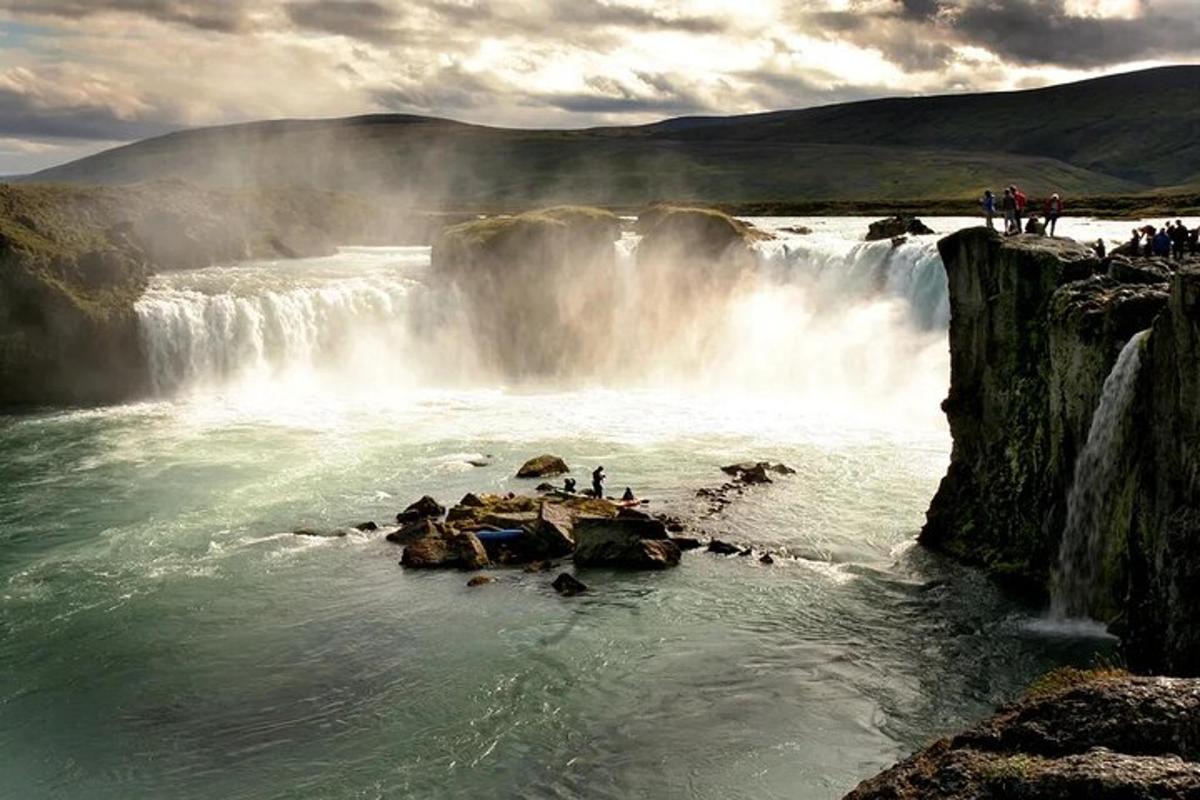 a group of people standing on rocks near a waterfall