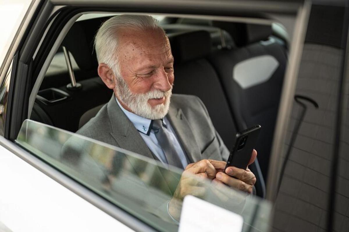 mees istub autos ja vaatab mobiiltelefoni