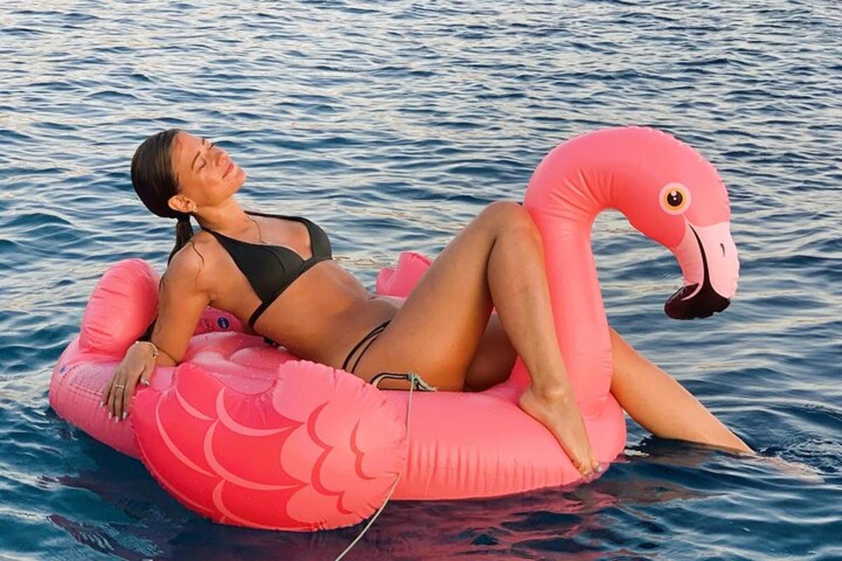 žena v bikinách ležící na růžovém plameňákovi ve vodě