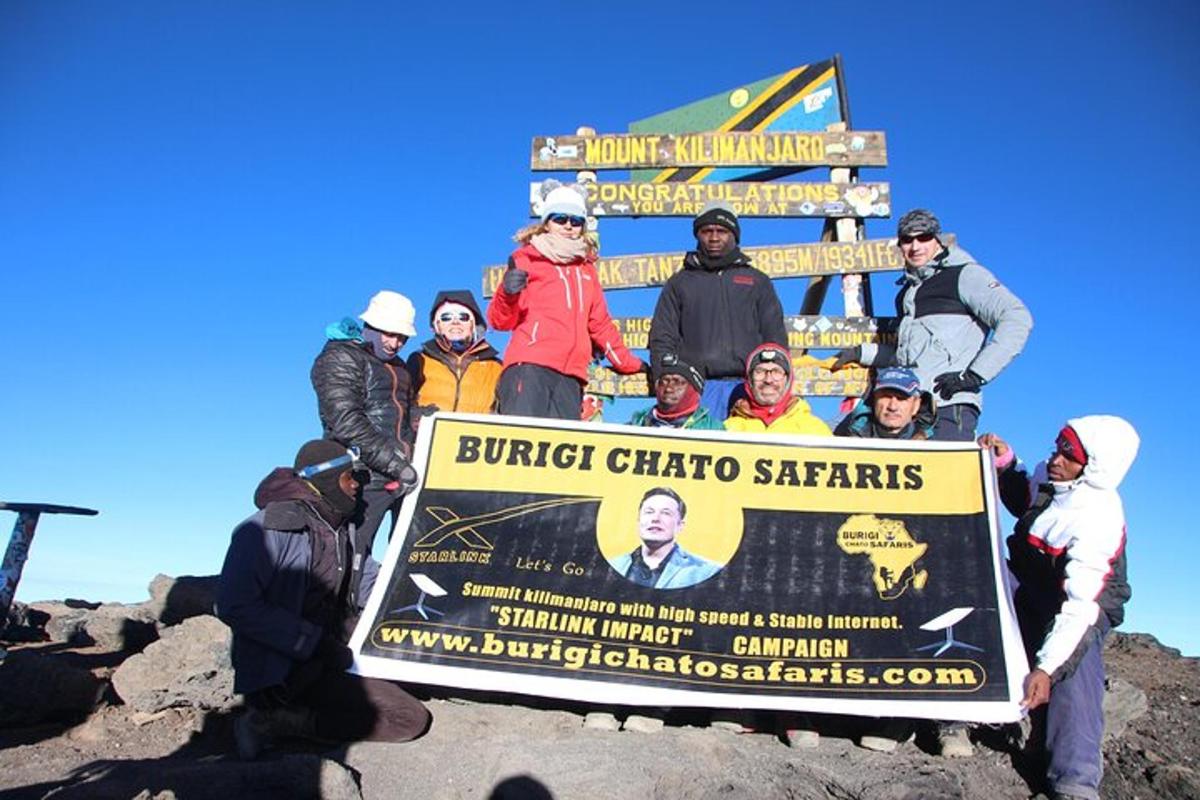 Un grupo de personas sosteniendo un gran cartel en la cima de una montaña.