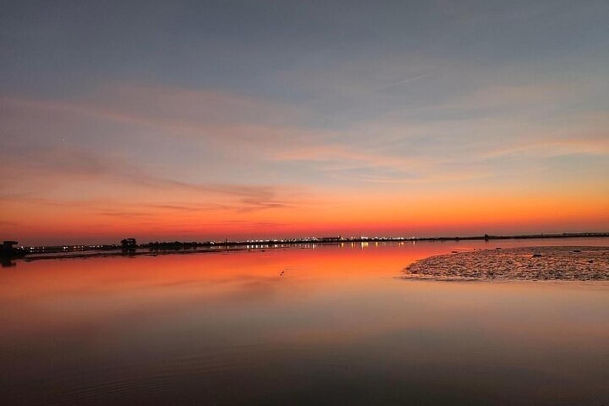 una massa d'aigua amb una posta de sol al fons