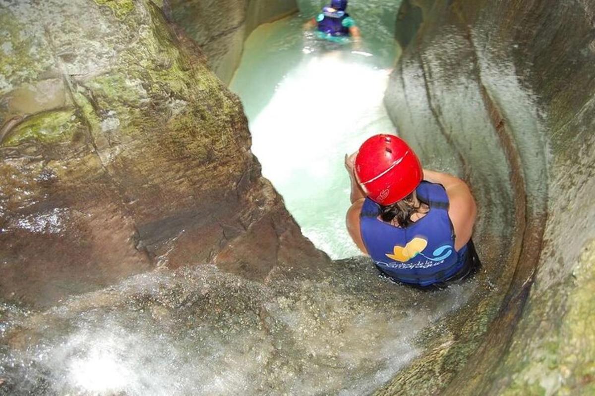 a woman is climbing up a rock in a waterfall
