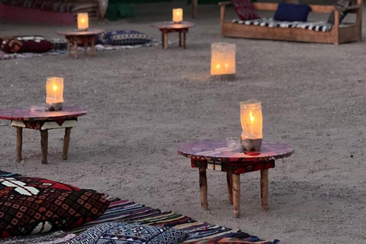 two candles sitting on tables in the sand