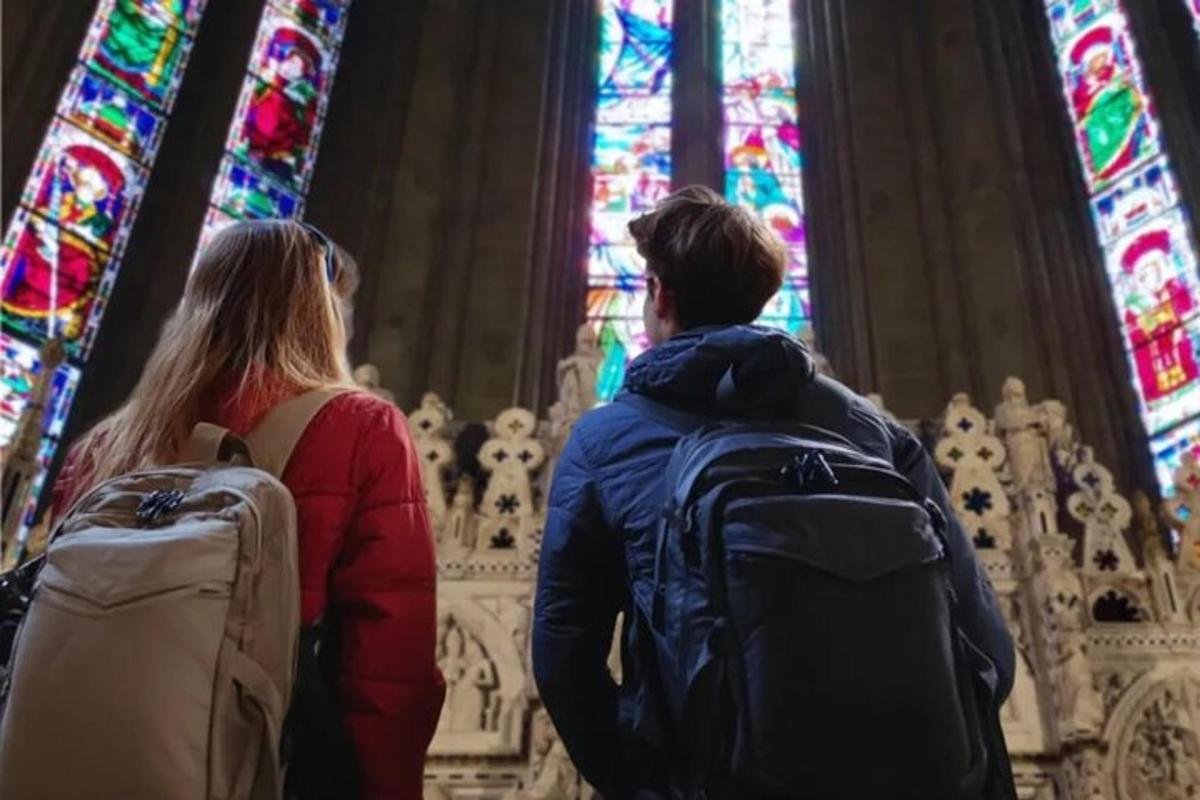 two people standing in a cathedral looking at stained glass windows