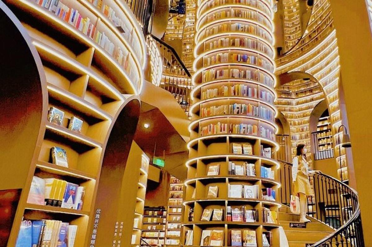 a library with books on shelves and a woman walking in front