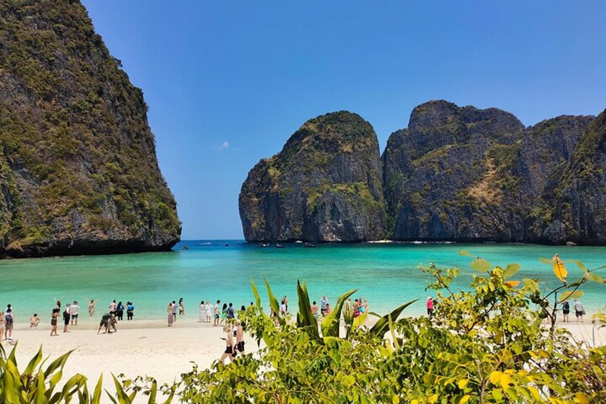 sekumpulan manusia di pantai dengan tebing batu kapur