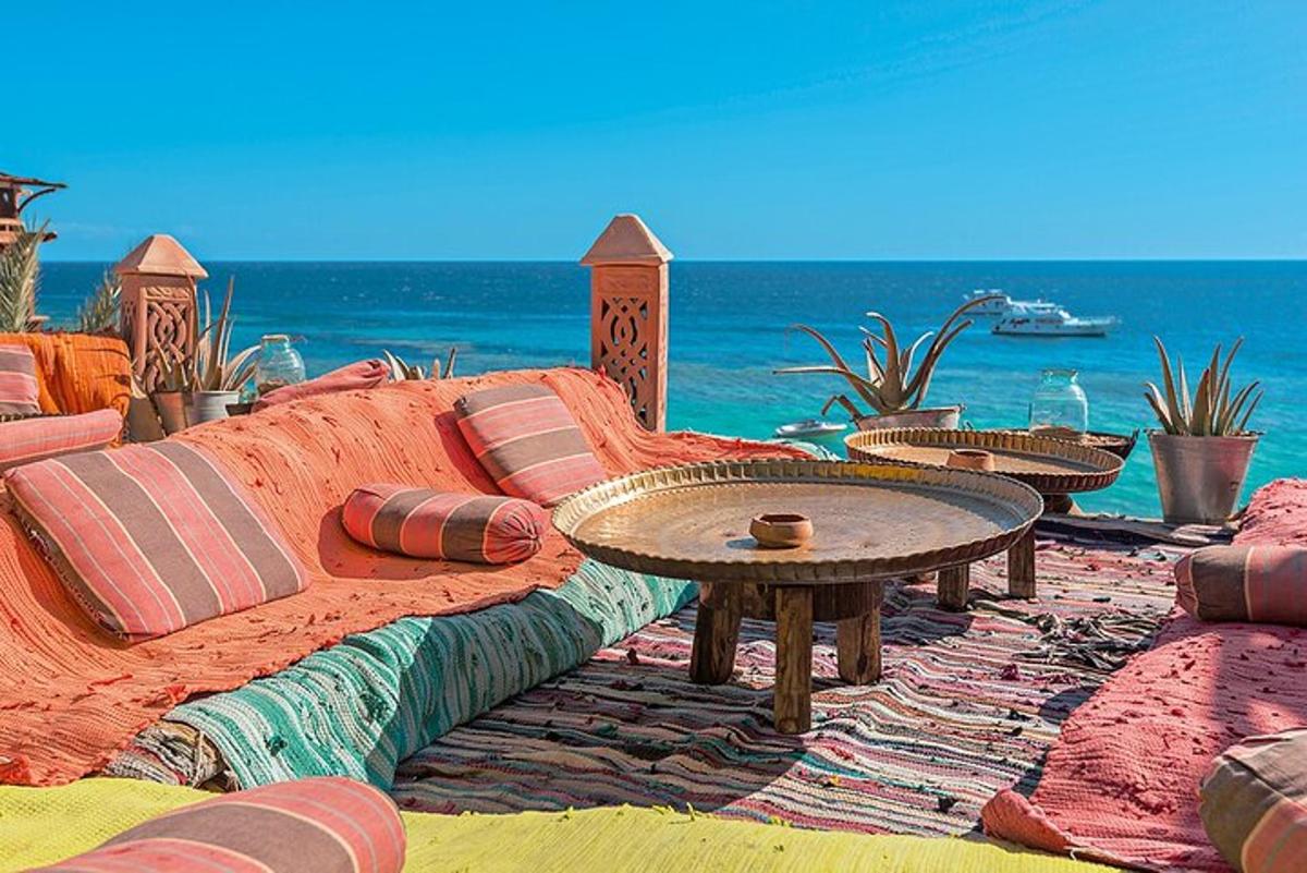a couch with pillows and a table on the beach