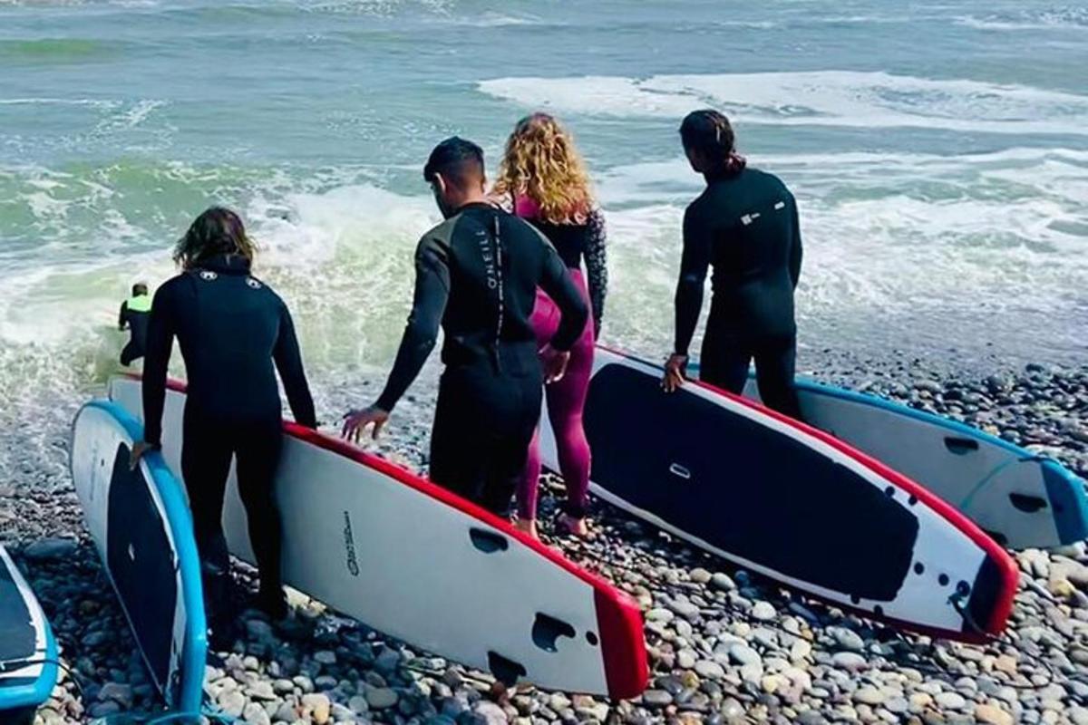 un gruppo di persone in piedi su una spiaggia che tengono in mano delle tavole da surf