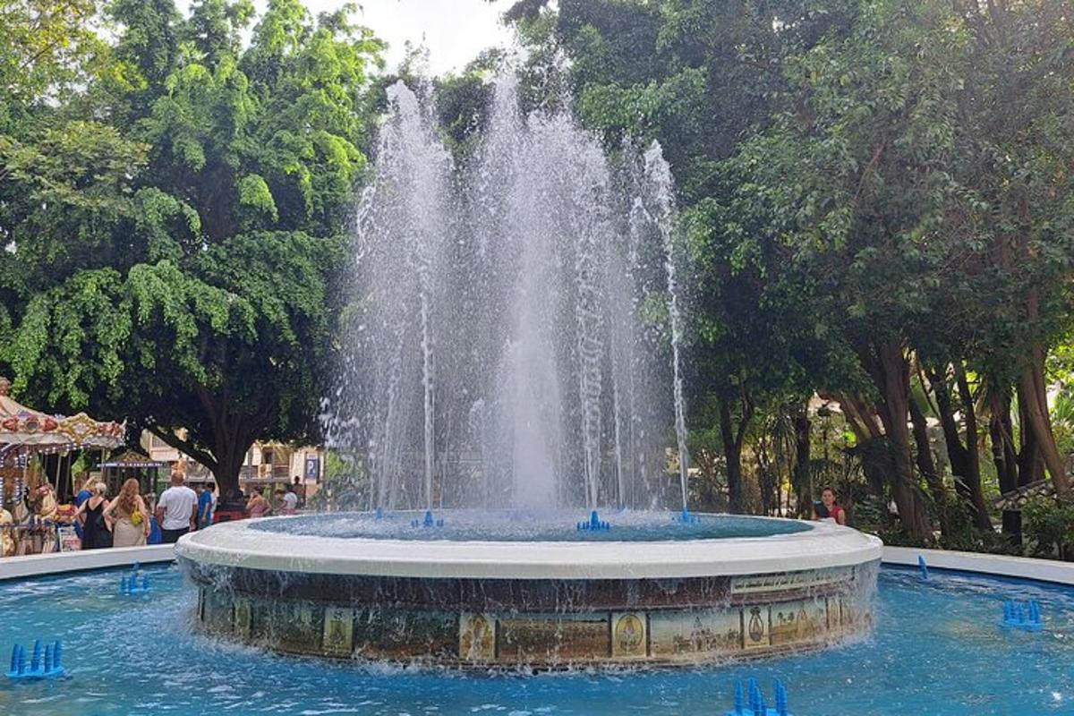 a fountain in a park with people sitting around it
