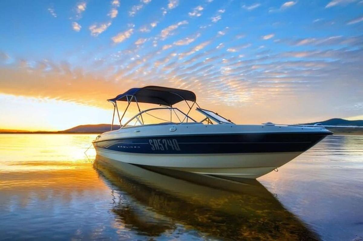 a boat sitting in the water at sunset