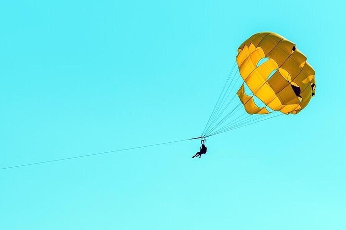 een persoon die met een parachute in de lucht vliegt