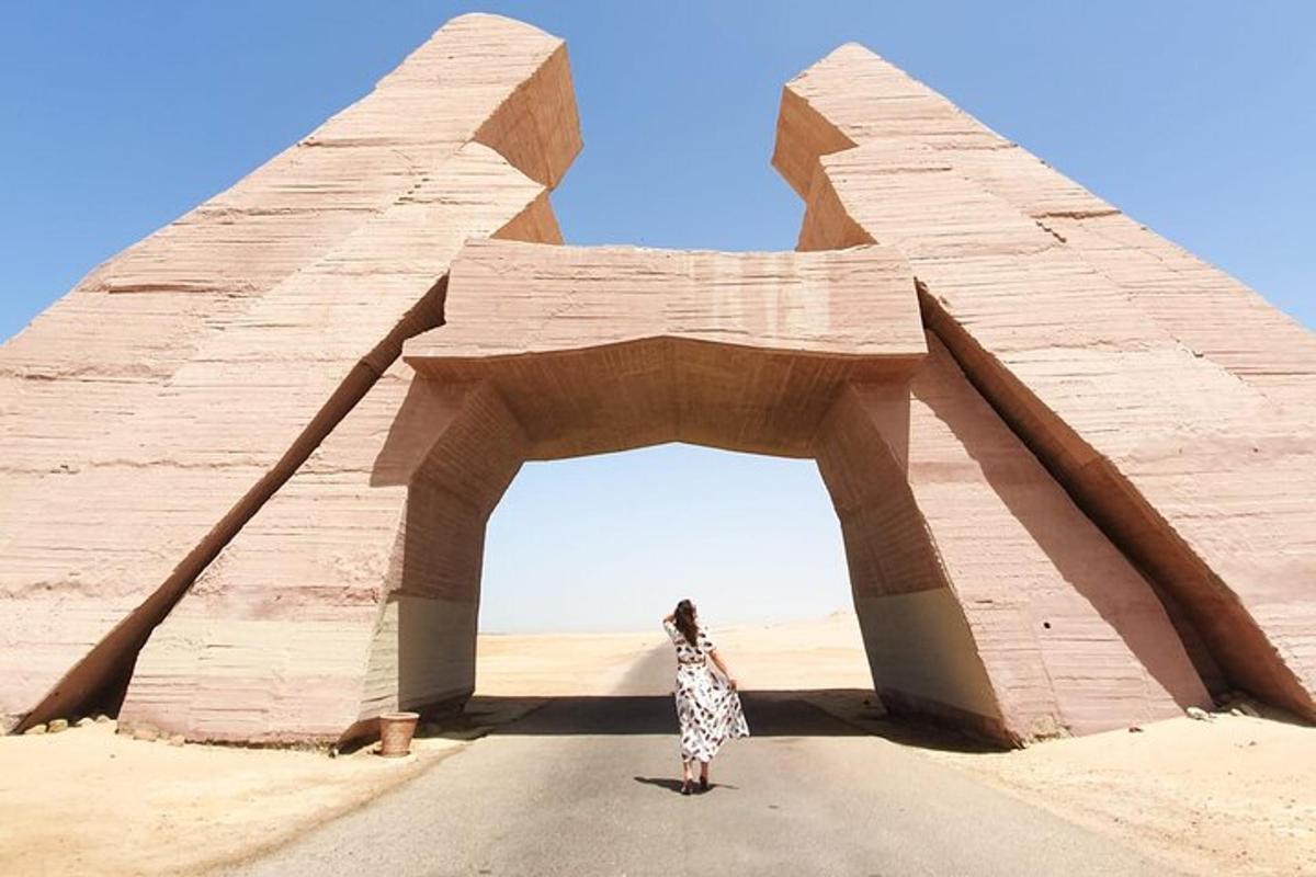 Una mujer parada frente a un arco en el desierto.