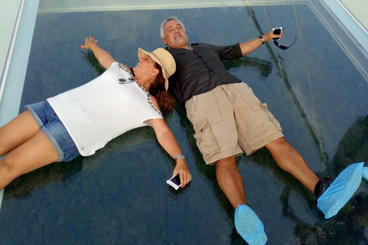 a man and woman laying on top of a glass ceiling