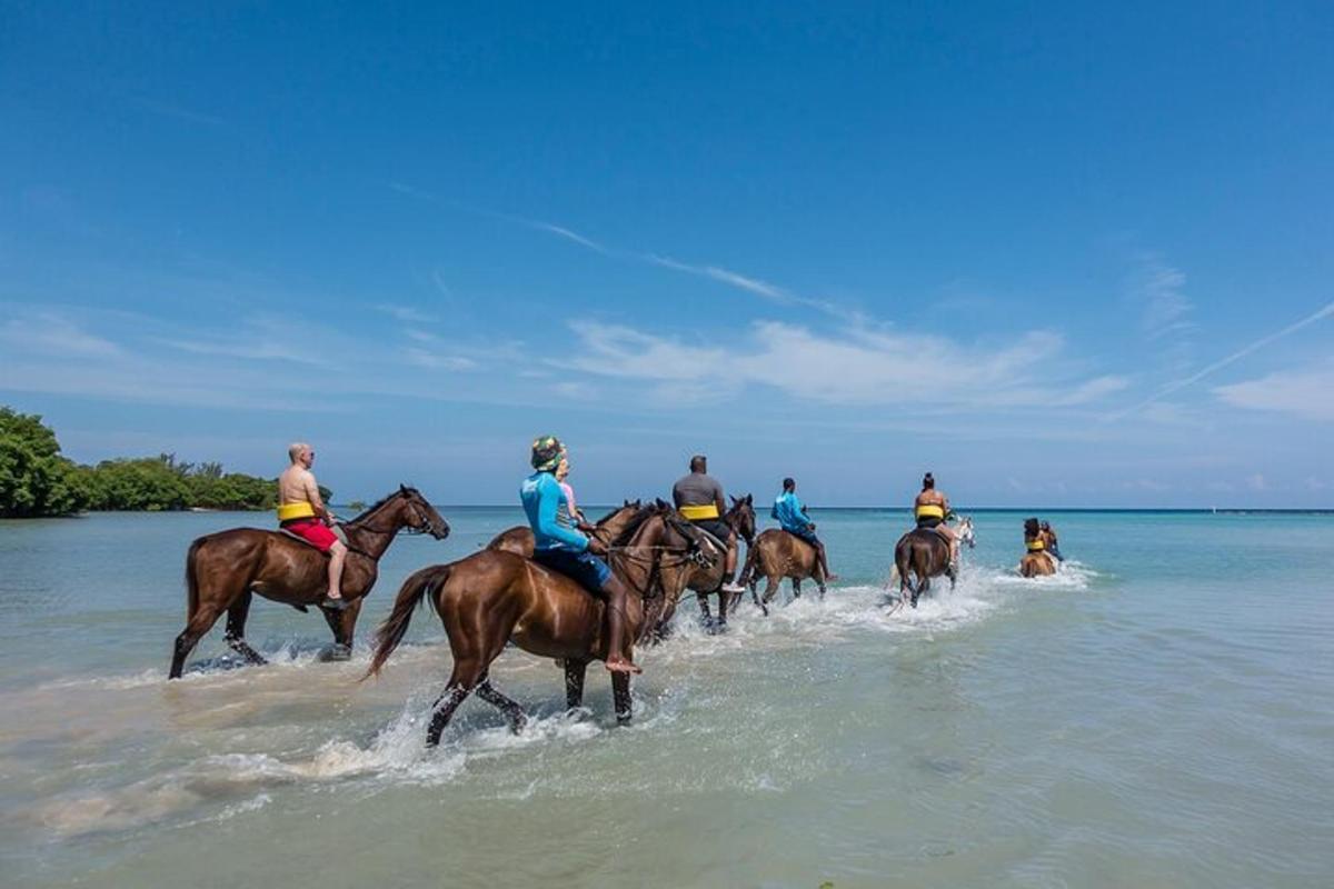 a group of people riding horses on the beach