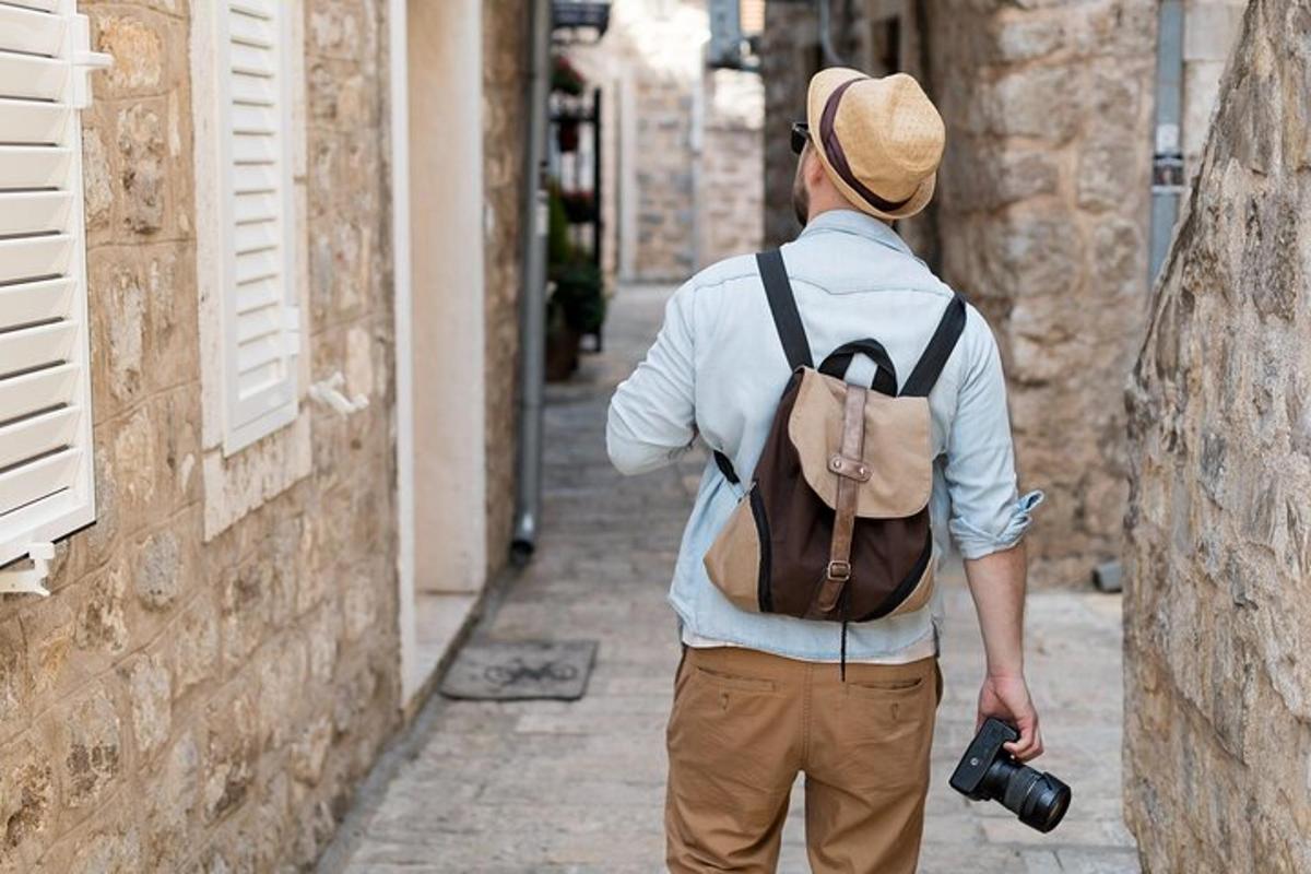 Ein Mann mit einem Rucksack geht mit einer Kamera eine Straße entlang