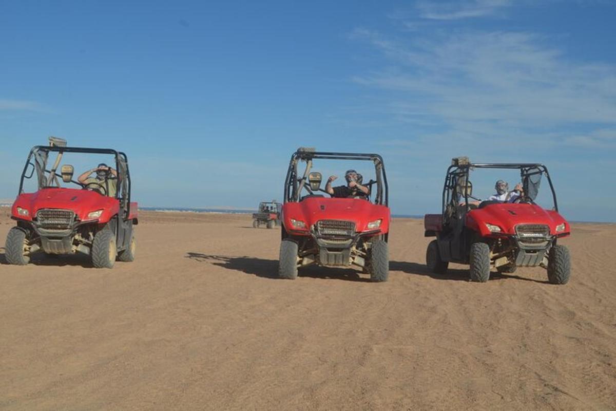 drei Personen fahren mit Geländefahrzeugen am Strand
