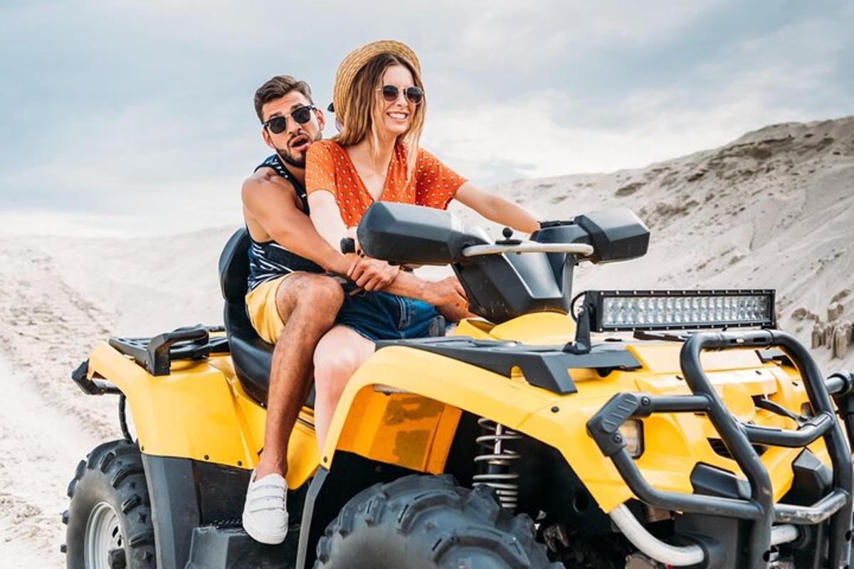 seorang lelaki dan wanita menunggang basikal quad di dalam pasir