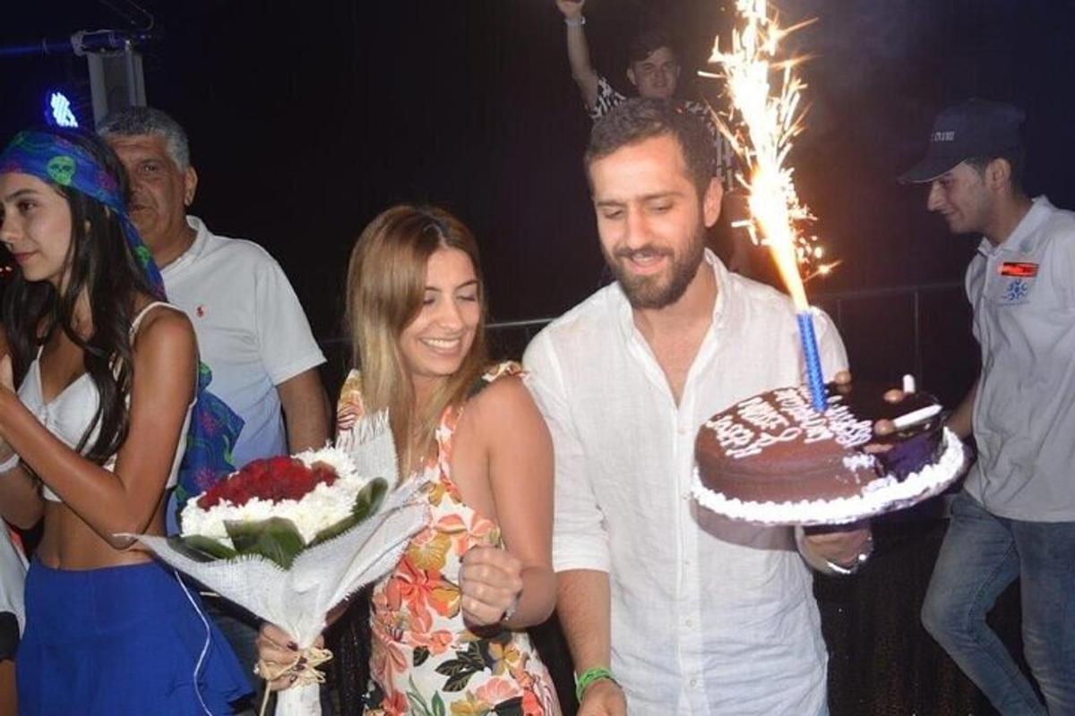 un uomo e una donna che tengono in mano una torta di compleanno con delle stelle filanti