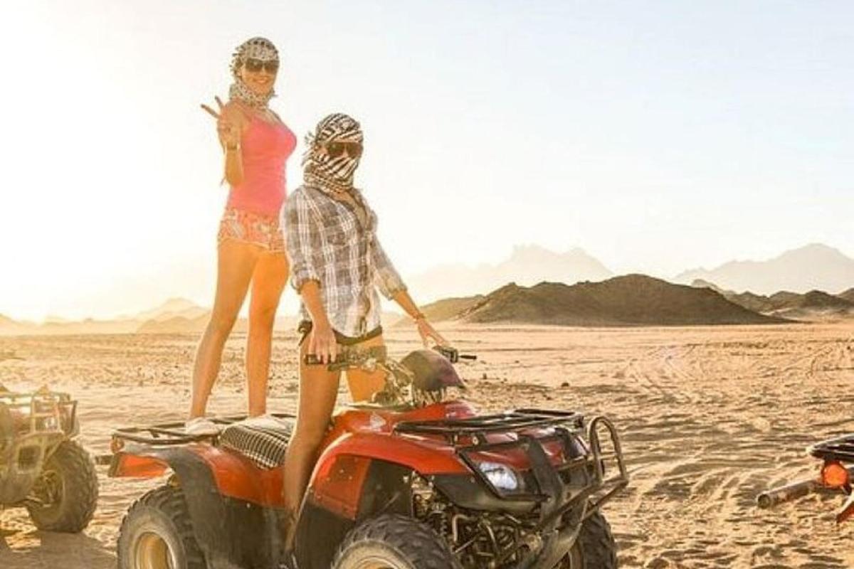 two people standing on a quad bike in the desert
