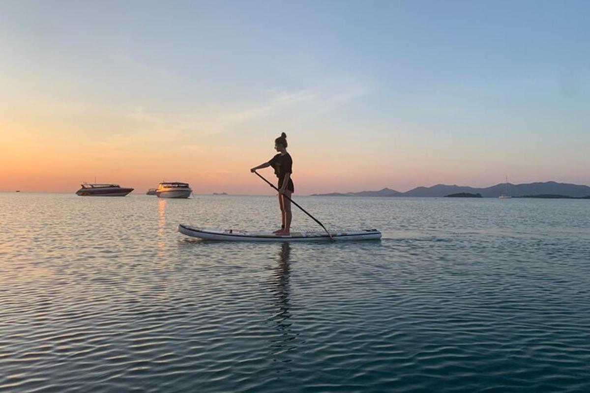una persona in piedi su una tavola da paddle in acqua