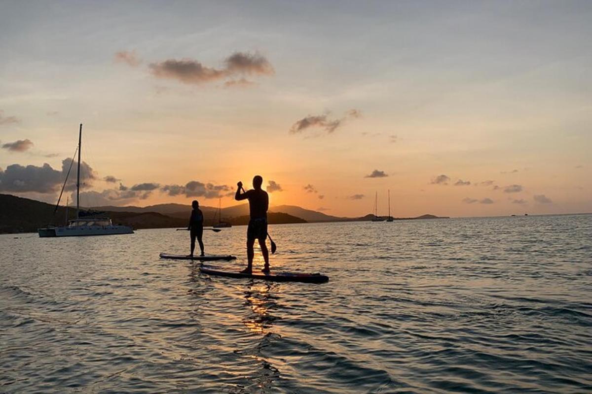 two people on paddle boards in the water at sunset
