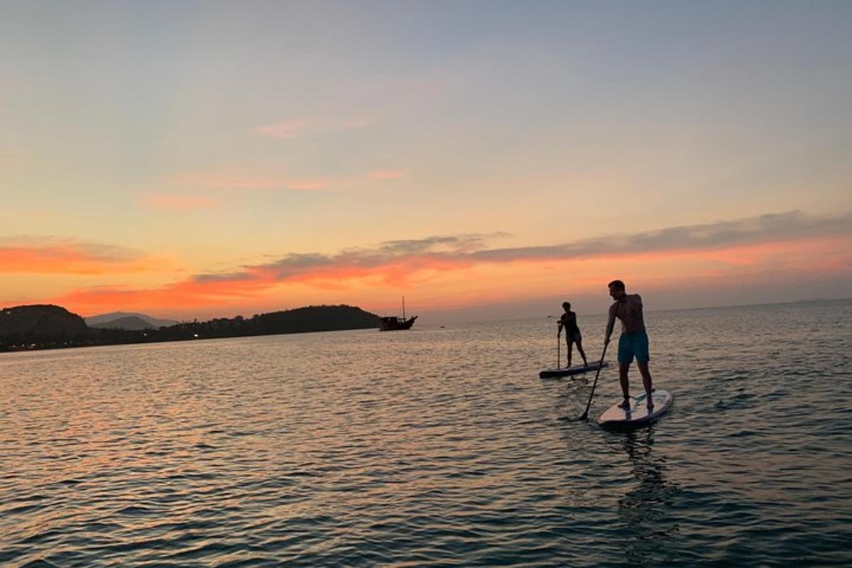 two people on paddle boards in the water at sunset
