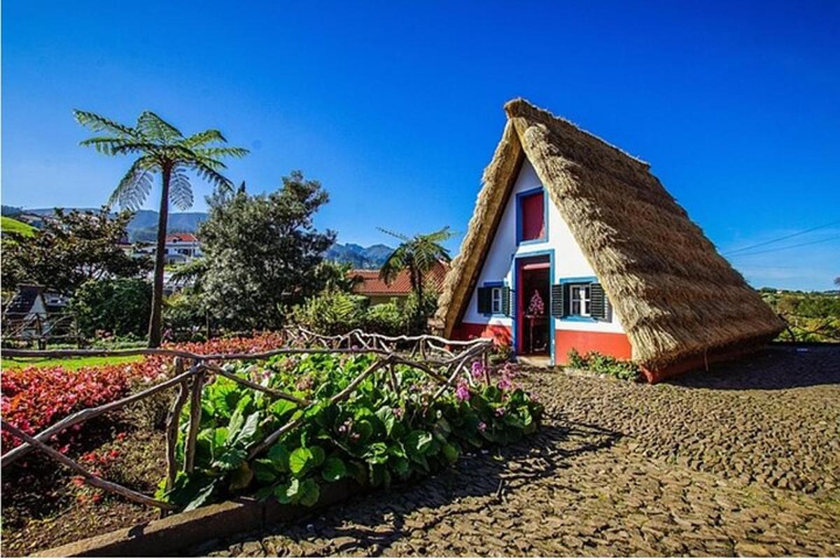 una petita casa amb teulada de palla en un jardí