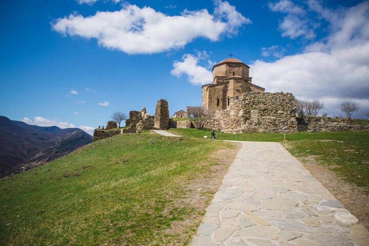 un antic castell en un turó amb un camí de terra
