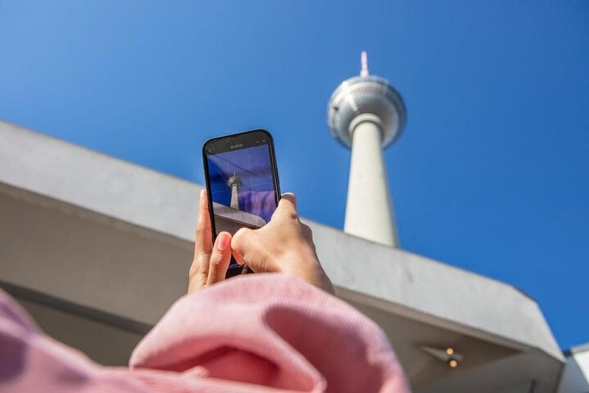 a person holding up a cell phone in front of a tower