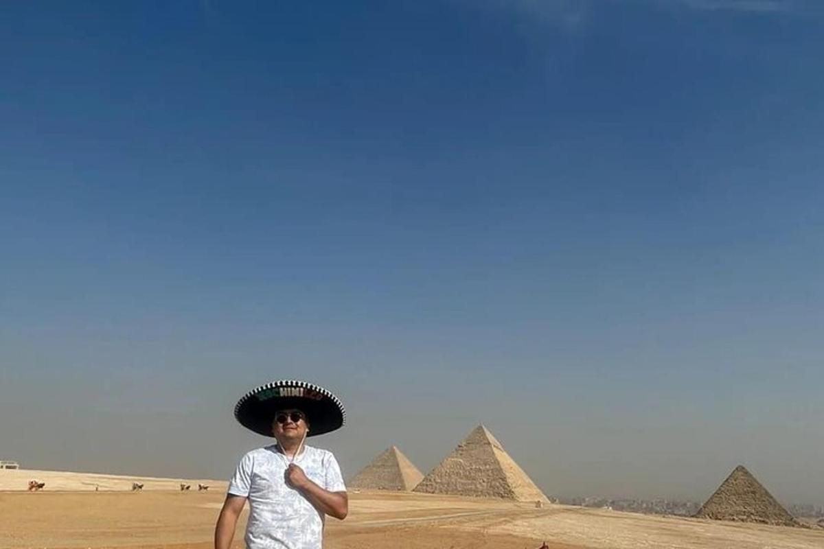 Un hombre con sombrero parado frente a las pirámides.