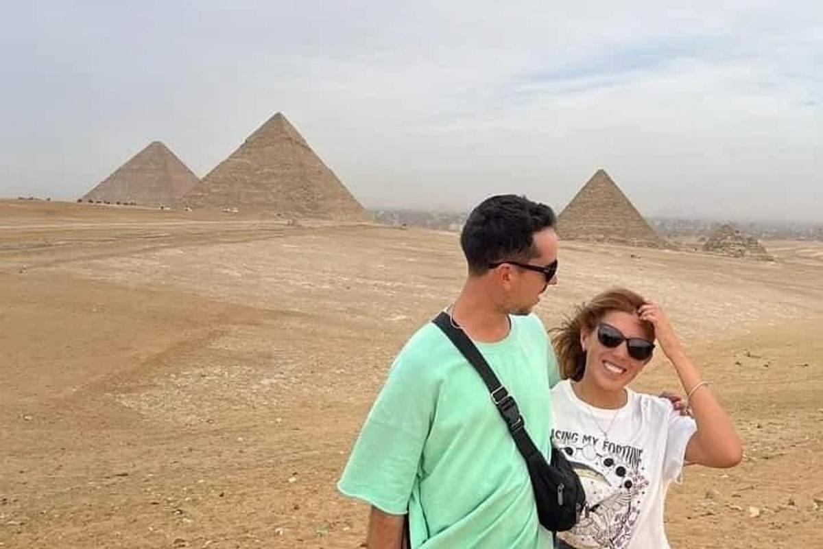Un hombre y una mujer de pie frente a las pirámides.