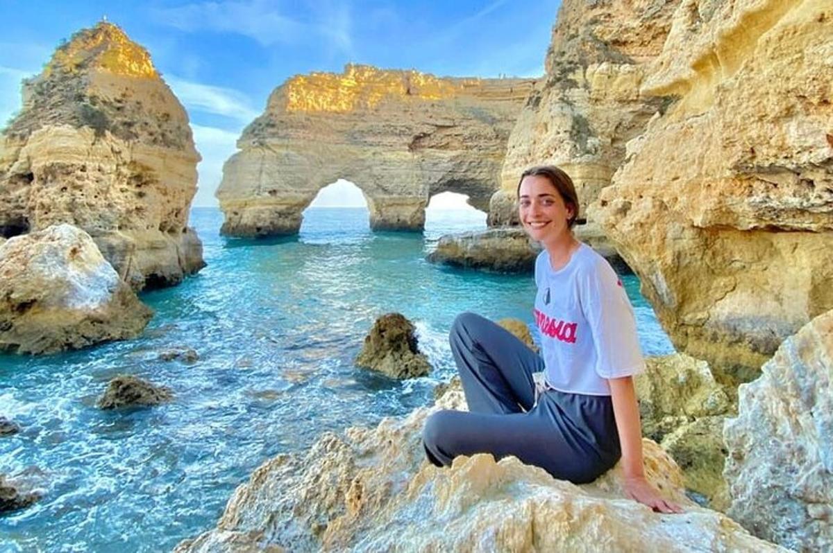 seorang wanita duduk di atas batu di depan lengkungan di air