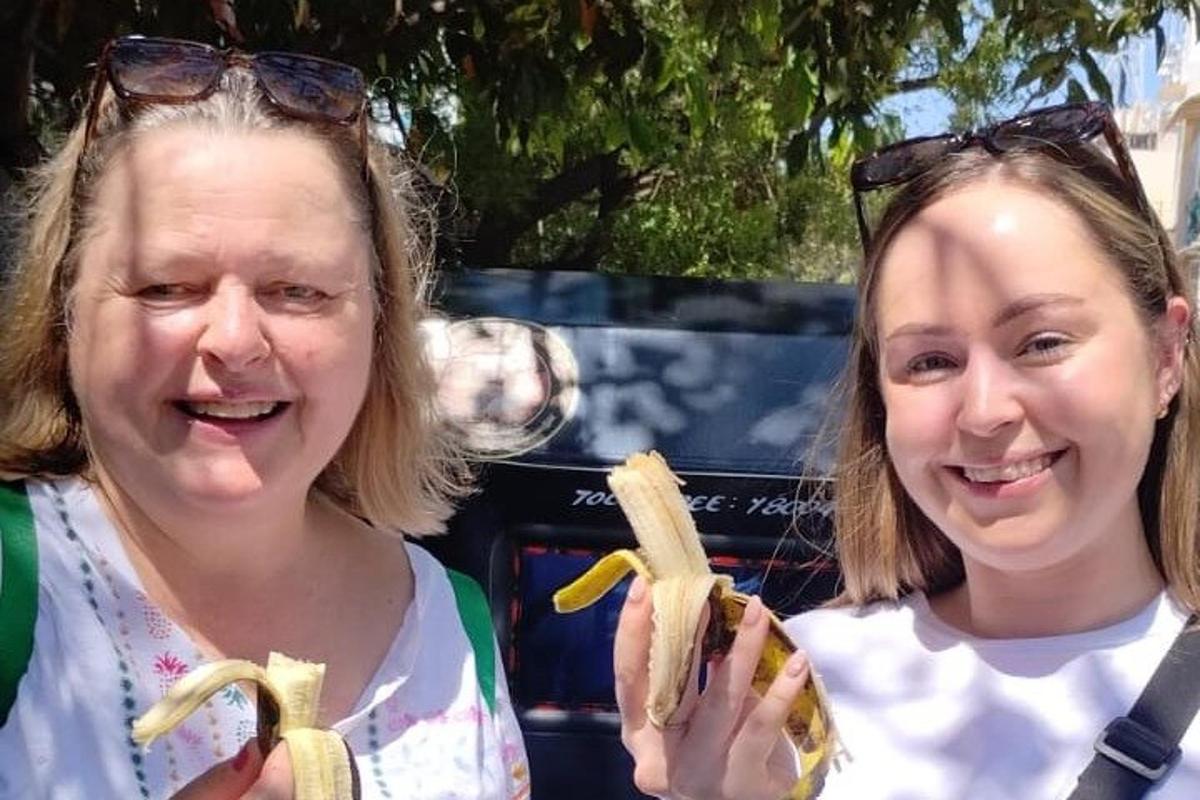 two women are smiling while holding peeled bananas